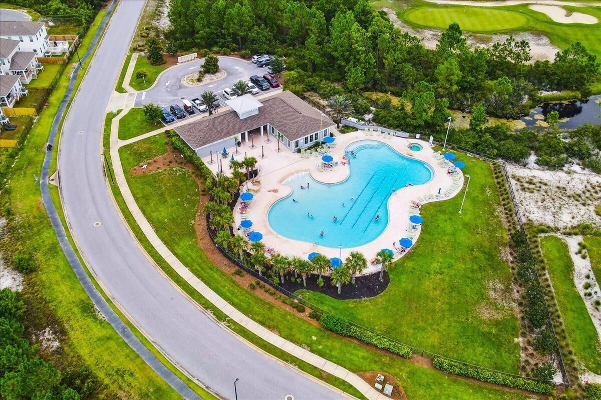 Vue aérienne d’un complexe hôtelier doté d’une grande piscine, d’un terrain de golf et d’une route qui serpente autour de l’établissement.