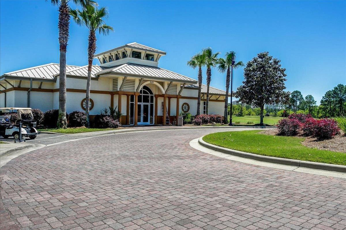 A building with a curved driveway, palm trees, and a golf cart.