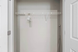 Un armario blanco con una estantería metálica y una barra para colgar ropa.
