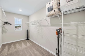 A laundry room with a drying rack, a vacuum cleaner, and storage shelves. - Wesley Chapel 4BR | Near Epperson Lagoon (Wesley Chapel)