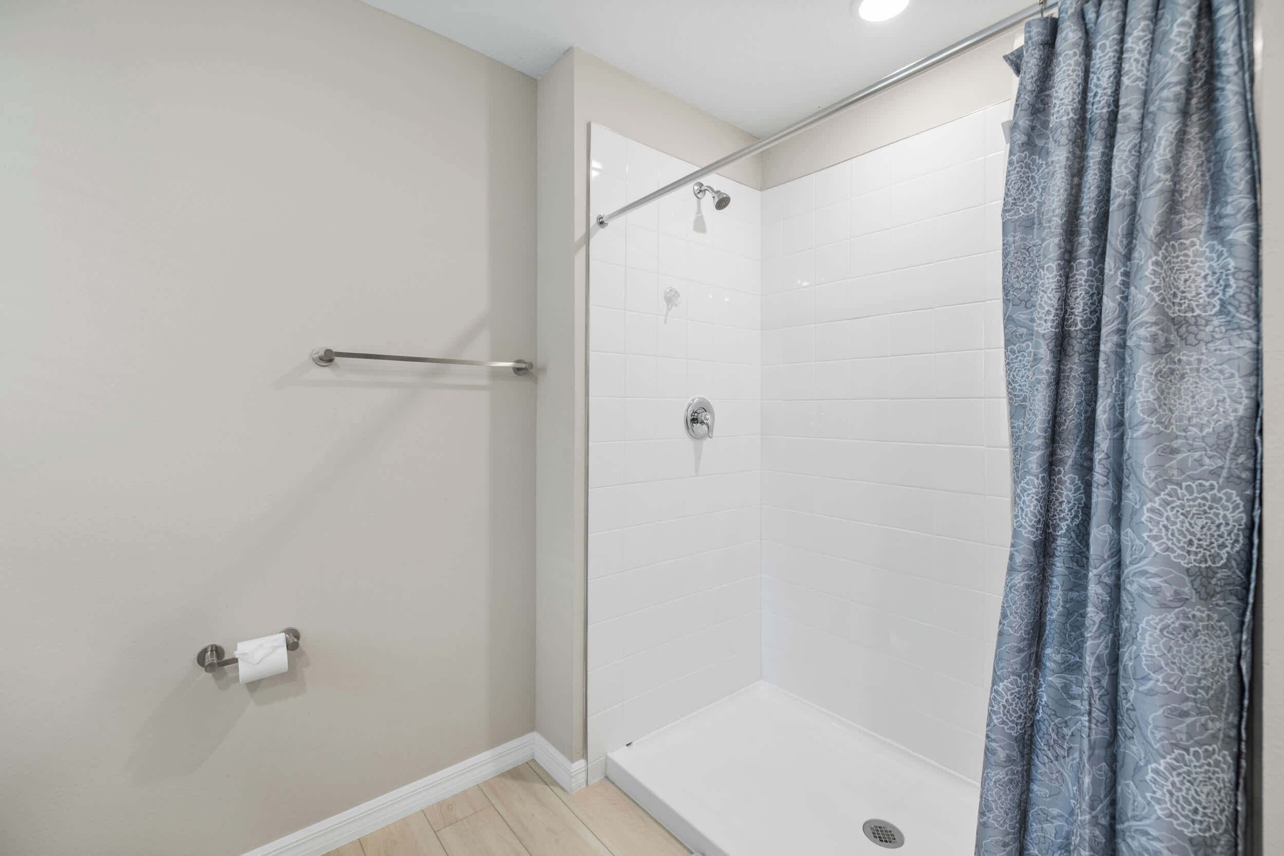 A shower with a glass door, a towel rack, and a toilet paper holder.
