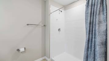 A shower with a glass door, a towel rack, and a toilet paper holder.