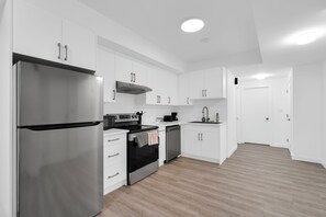 Una cocina moderna con armarios blancos, electrodomésticos de acero inoxidable y suelo de madera.