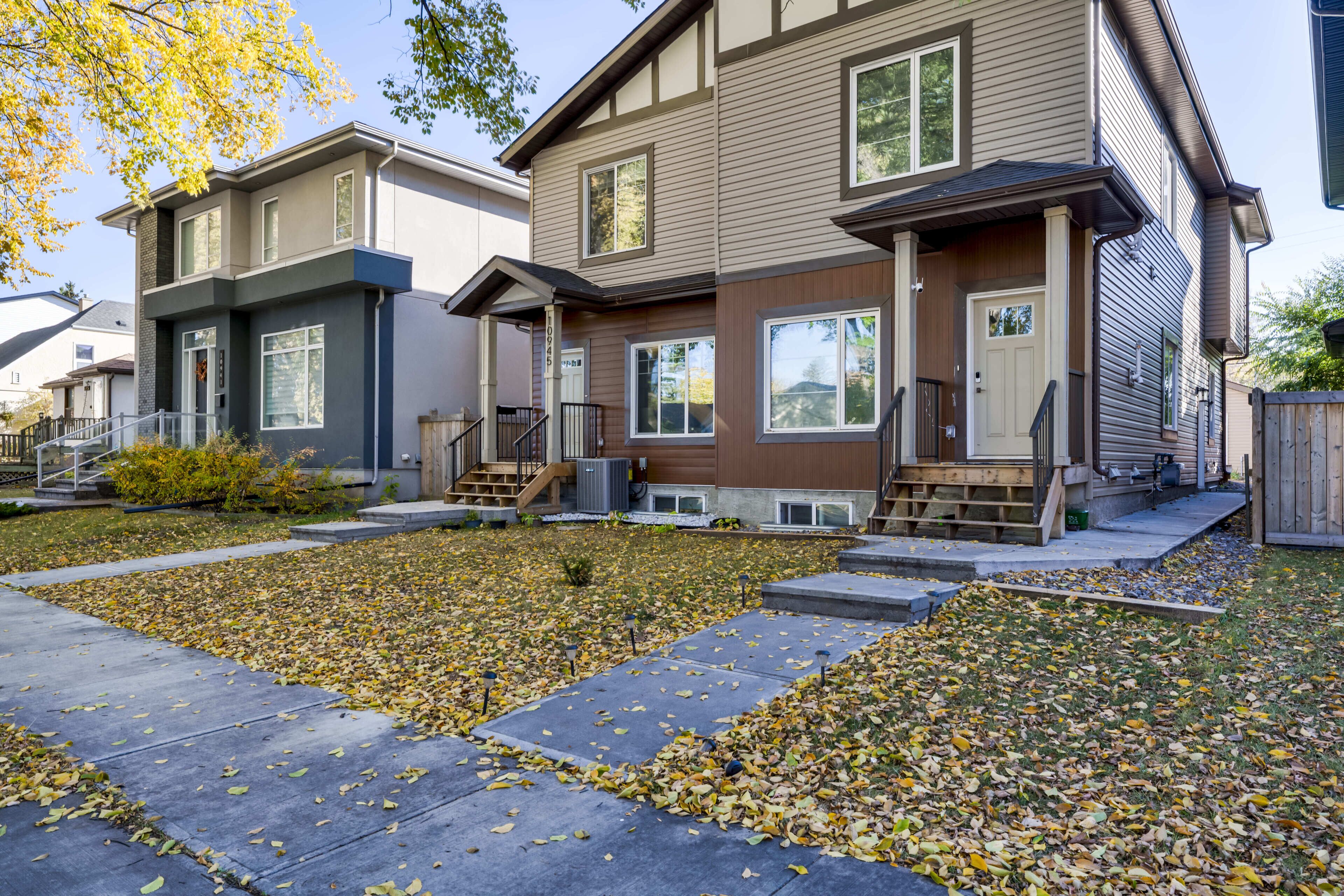 A row of townhouses with a front yard, a wooden deck, and a clear sky.