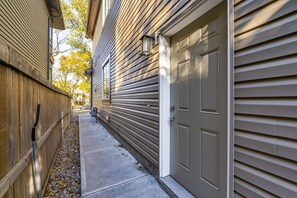 A narrow driveway leading to a garage with a wooden fence on one side and a house with horizontal siding on the other. - 4BHK Close to Downtown/Whyte Ave/UOFA (Edmonton)