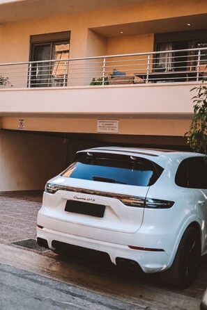 Ein weißer SUV steht in einer überdachten Parkgarage, darüber befindet sich ein Balkon.