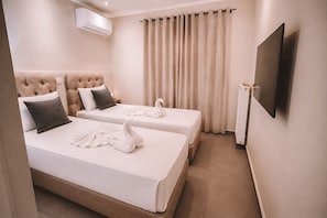 Ein Hotelzimmer mit zwei Betten, einem Fernseher und einer Klimaanlage.