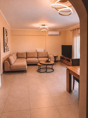 Ein Wohnzimmer mit Ecksofa, Couchtisch, TV-Schrank und Kamin.
