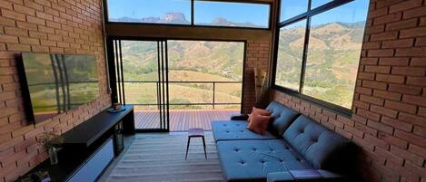 Una sala de estar moderna con un ventanal grande, un sofá, un televisor y una pequeña mesa.