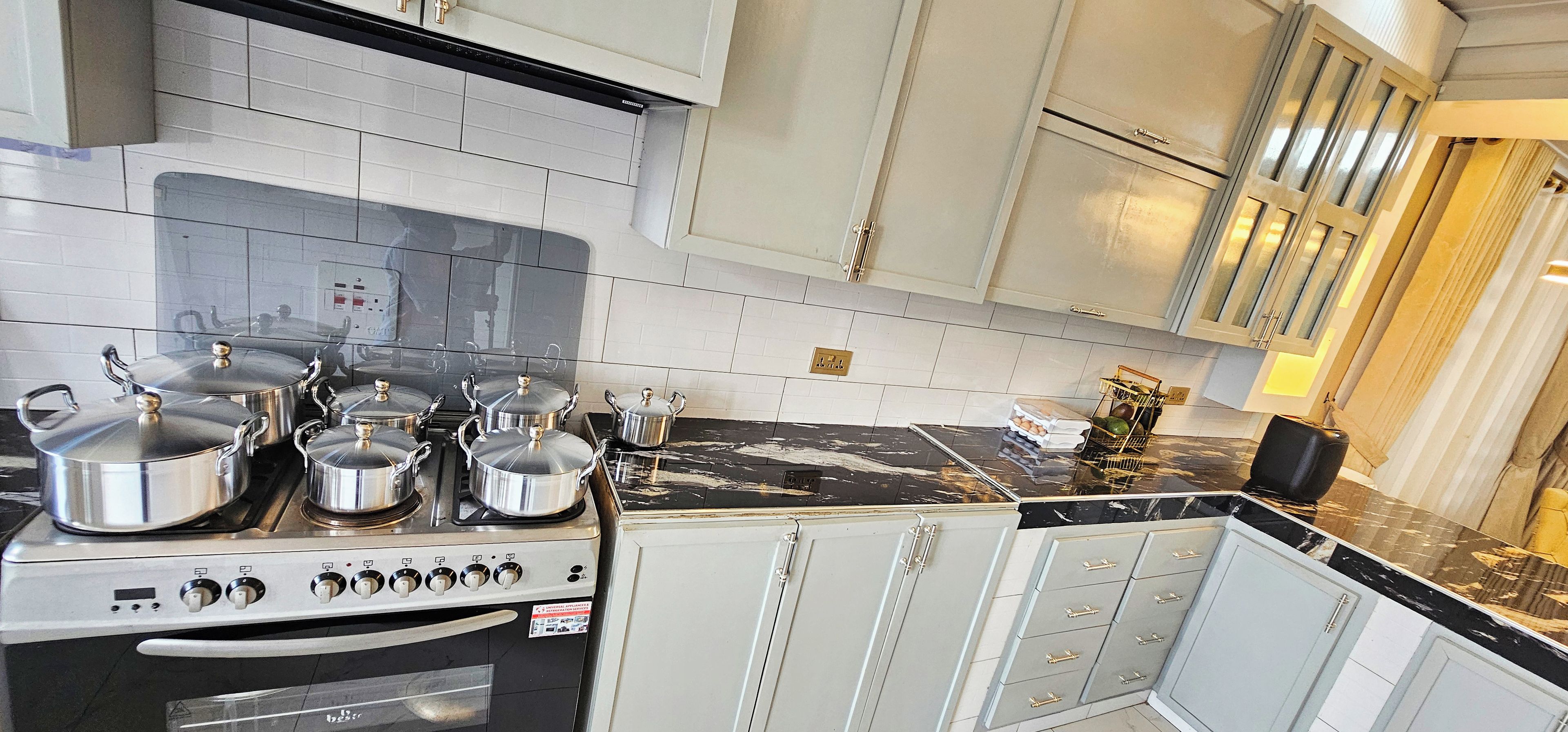 A kitchen with a stove, pots, and cabinets.