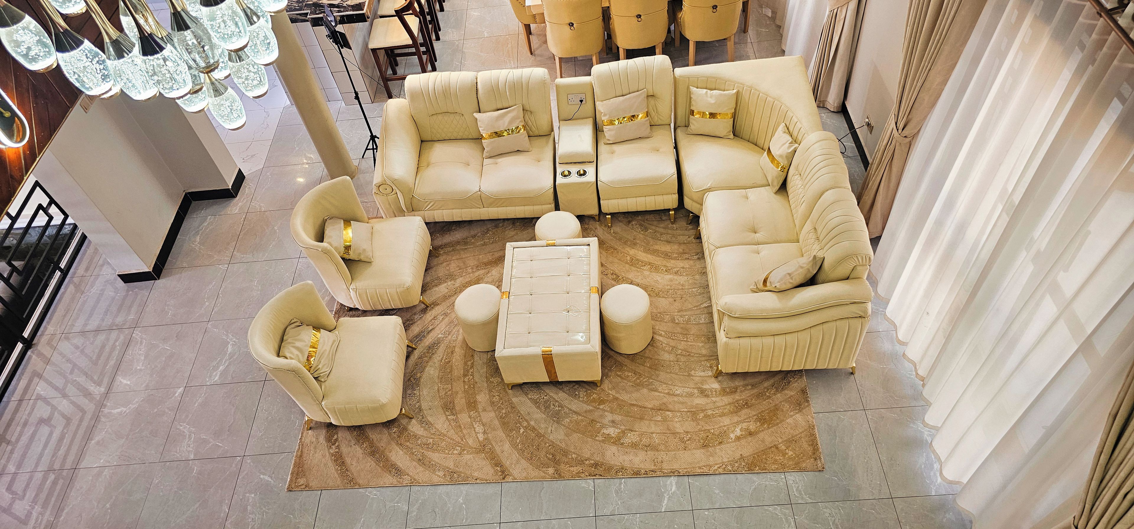 A modern living room with a sectional sofa, armchairs, a coffee table, and a patterned rug.