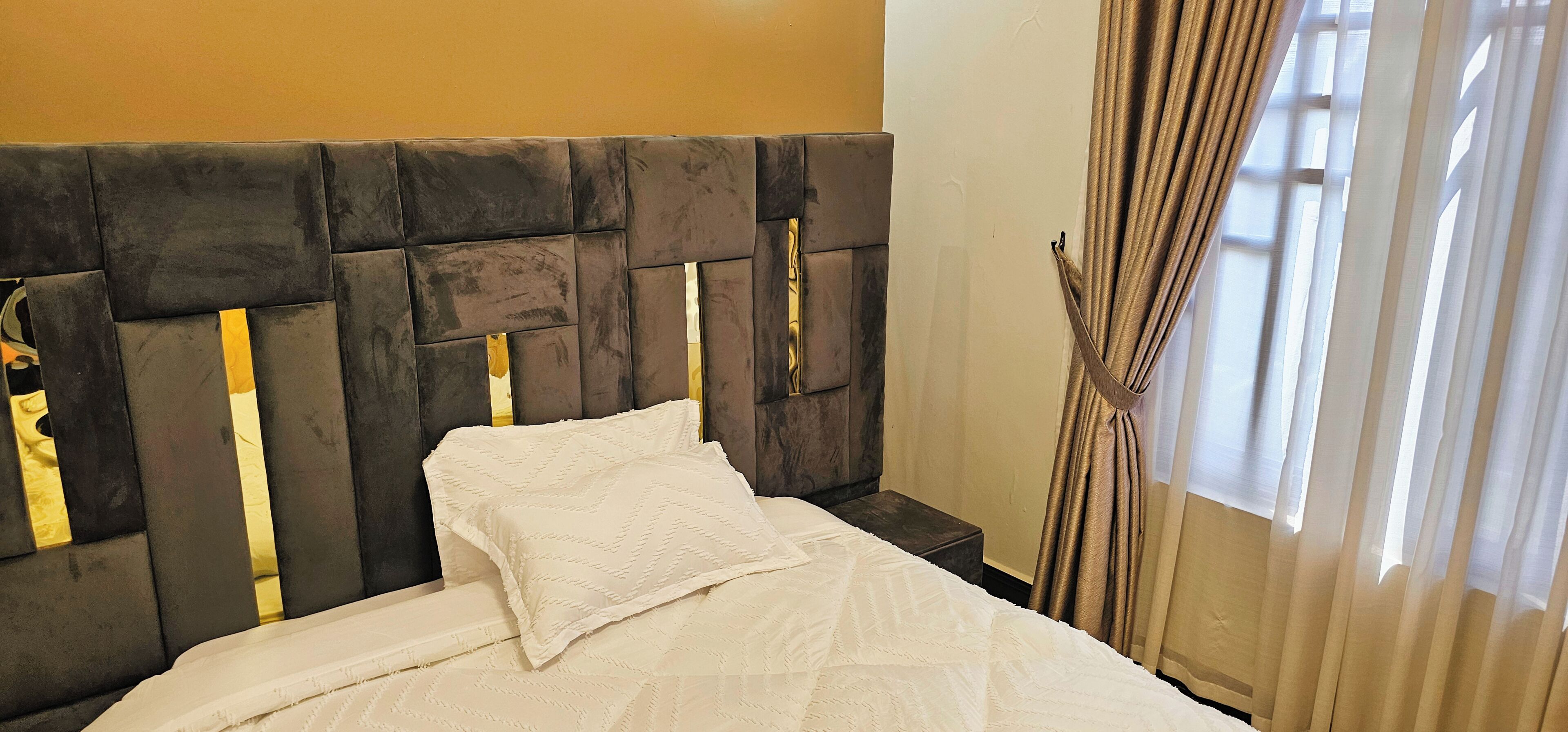 A bed with a headboard, a nightstand, and curtains.