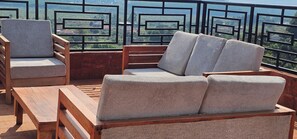 A balcony with a wooden bench, two cushioned chairs, and a view of a green landscape. - Babz Residence, A private countryside retreat in a serene natural setting (Lutaba Trading Centre)