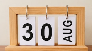 Ein Holztischkalender mit drei weißen Karten, die den 30. August zeigen.
