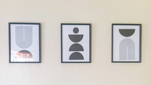 Drei gerahmte abstrakte Kunstwerke an einer Wand über einem blauen Sofa.