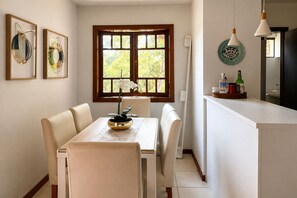 Un coin repas comprenant une table, des chaises et une fenêtre donnant sur la forêt.