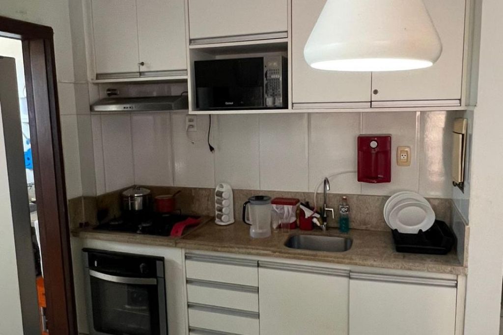 Cozinha compacta com micro-ondas, pia e escorredor de louça.
