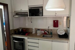 A compact kitchen with a microwave, sink, and a dish rack. - Guest House Praia do Forte Apartment with Gourmet Balcony and access to the pool. (Açu da Torre)