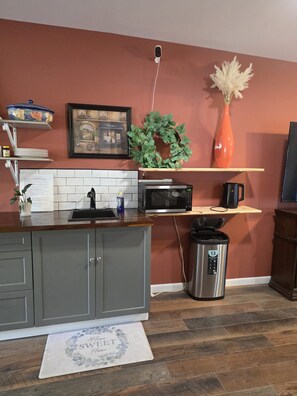 A kitchen with a microwave, sink, and a trash can.