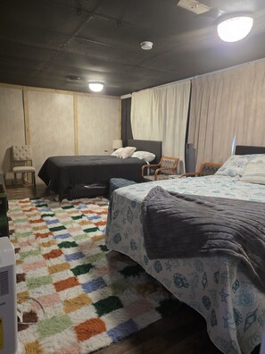 Une chambre d’hôtel avec deux lits, un tapis à motifs et un ventilateur de plafond.