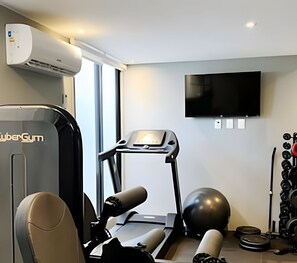 Ein Heimfitnessraum mit Laufband, Ergometer und Gewichten.