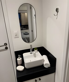 Ein Badezimmer mit einem weißen Waschbecken, einem Spiegel, einem Handtuch und einer kleinen Topfpflanze.