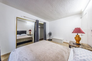 A hotel room with a bed, a bedside table with a lamp, a mirror, a fan, and a wardrobe. - Pretty apartment (Los Angeles)