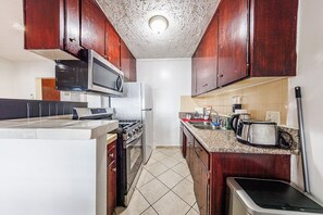 A kitchen with wooden cabinets, a microwave, a stove, and a sink. - Pretty apartment (Los Angeles)