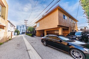 A narrow street with parked cars and a two-story building with a garage. - Pretty apartment (Los Angeles)