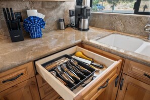 A kitchen with a drawer organizer containing utensils, a coffee maker, and a kettle. - Indian Hills Townhome (Truckee)