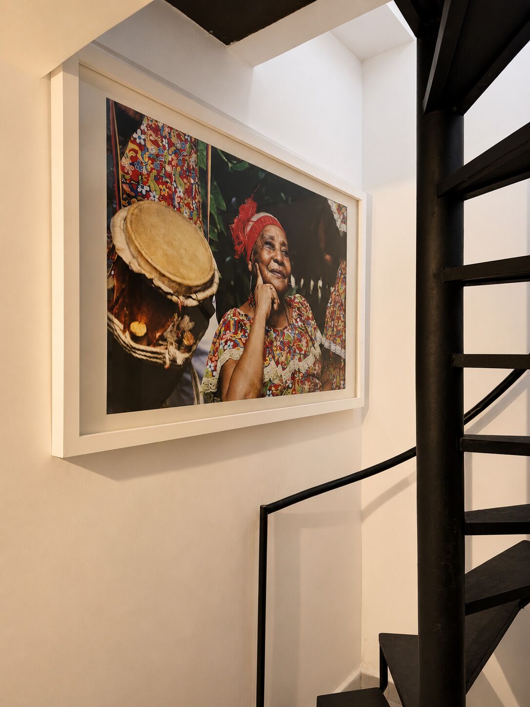 A framed photograph on a wall, a black metal staircase, and a white wall.