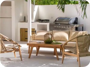 An outdoor seating area with a grill, a sofa, and two chairs. - Villa Elé, 4 bedrooms, tropical garden and pool (Orient Bay)