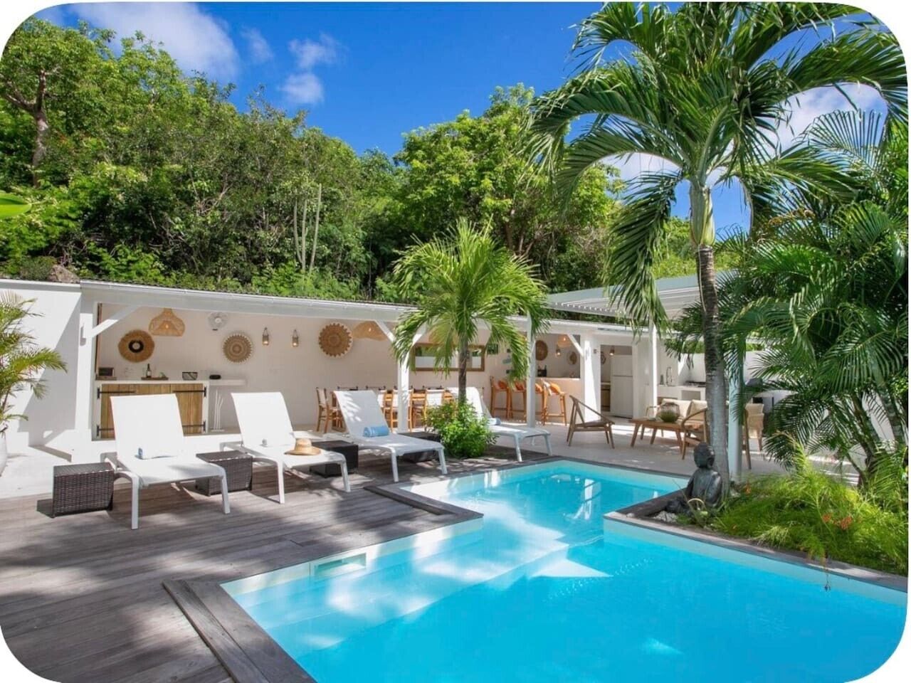 A pool area with lounge chairs and a statue, surrounded by lush greenery.