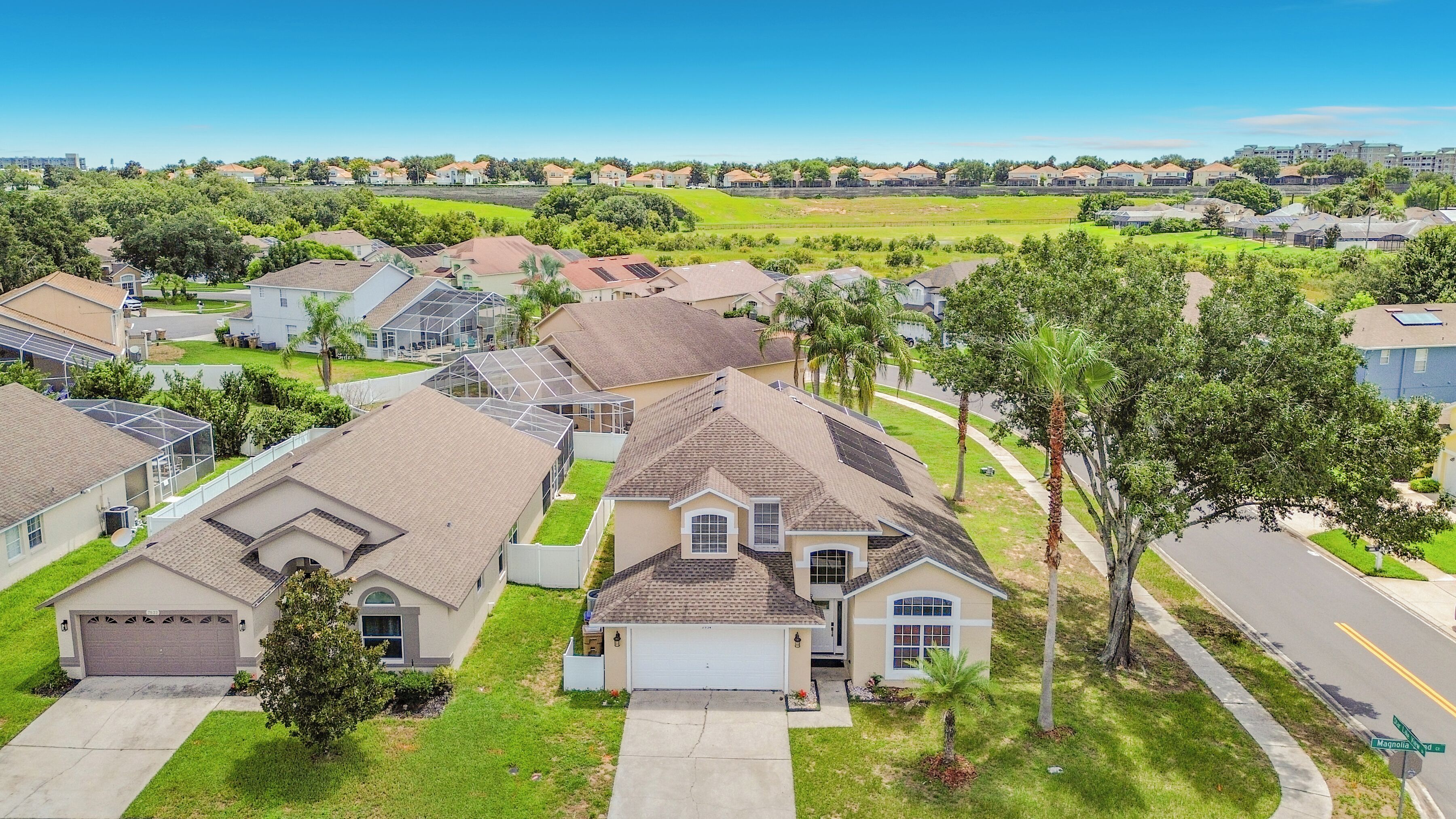A residential neighborhood with single-family homes, a clear sky, and a street named Magnolia.