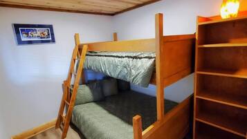 A bunk bed with a ladder, a shelf unit, and a framed picture on the wall.