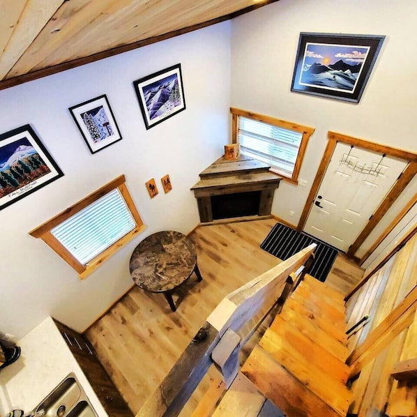 A wooden interior with a fireplace, a dining table, and a view of the outside.