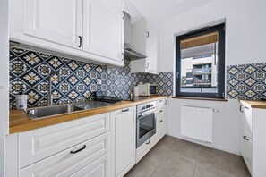 Eine Küche mit weißen Schränken, einer Holzarbeitsplatte, einem eingebauten Backofen und einem Fenster mit Aussicht.