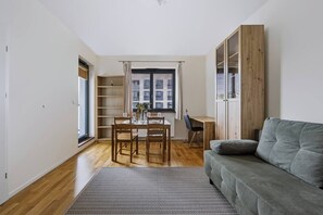 A compact living space with a dining area, a sofa, and a built-in wardrobe. - Warsaw Urban Wola Apt — Parking & Balcony (Warsaw)