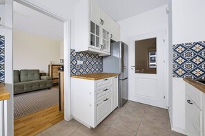 A compact kitchen with white cabinets, a wooden countertop, and a patterned backsplash. - Warsaw Urban Wola Apt — Parking & Balcony (Warsaw)