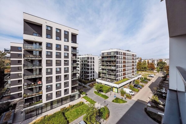 A modern apartment complex with multiple floors, balconies, and a central courtyard. - Warsaw Urban Wola Apt — Parking & Balcony (Warsaw)