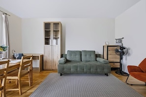 A living room with a grey sofa, wooden dining table, chairs, a cabinet, and a floor lamp. - Warsaw Urban Wola Apt — Parking & Balcony (Warsaw)