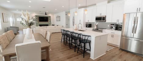 A modern kitchen with white cabinets, stainless steel appliances, and a central island with bar stools.