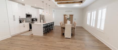A spacious kitchen with white cabinetry, a central island, and pendant lighting.