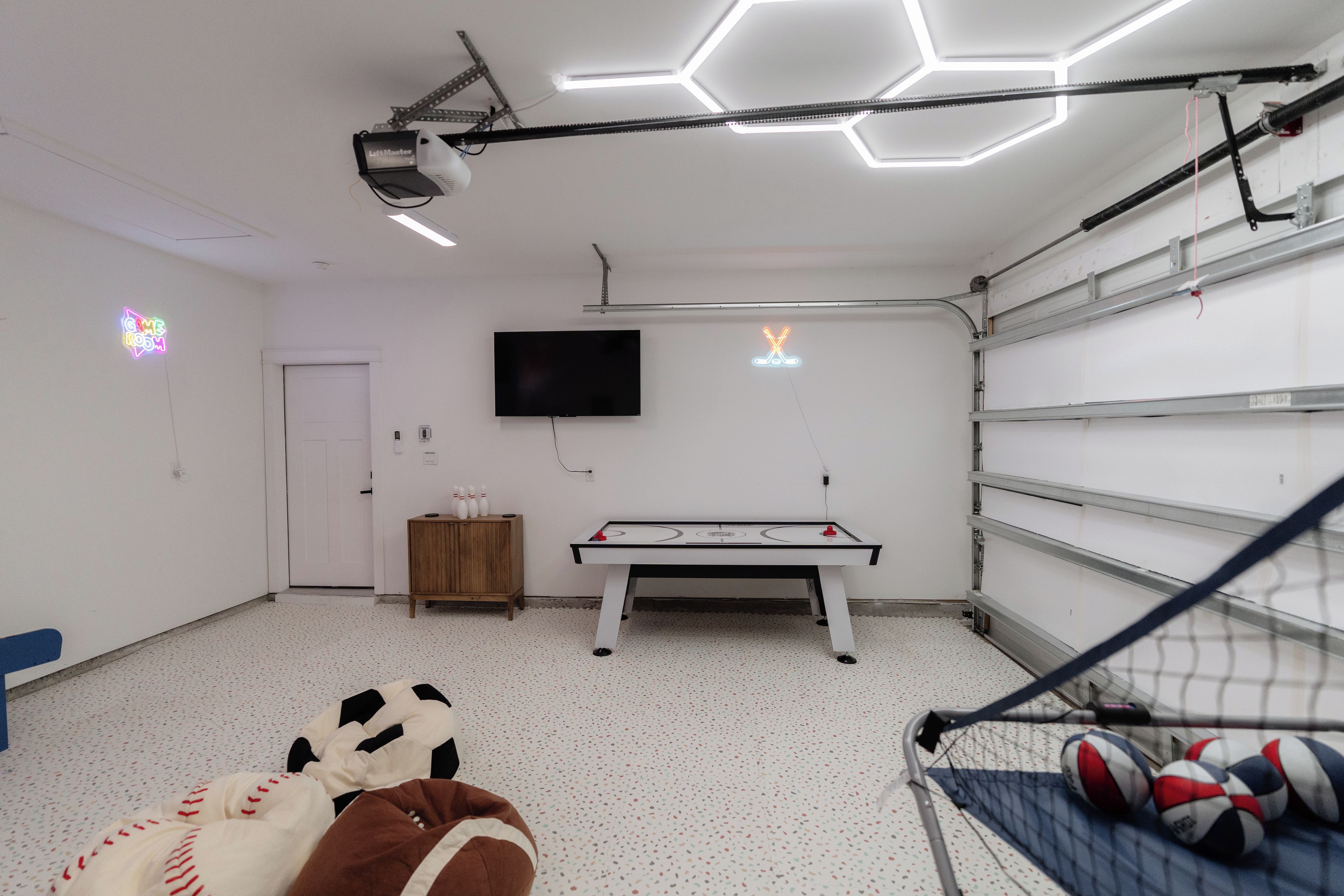 A room with a ping pong table, a television mounted on the wall, and a door.