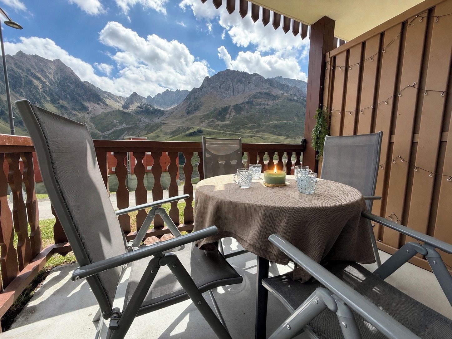 A balcony with a table set for two, overlooking a mountainous landscape.