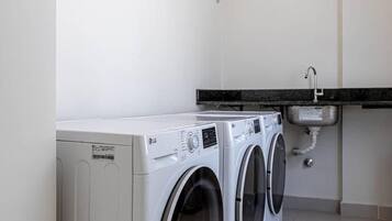 A laundry room with two front-loading washing machines and a sink.