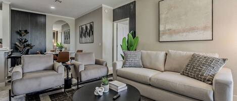 A modern living room with a sofa, two armchairs, a coffee table, and a dining area with chairs and a table.