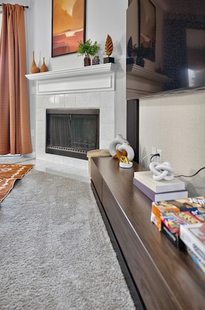 A living room with a fireplace, a television, and a bookshelf.