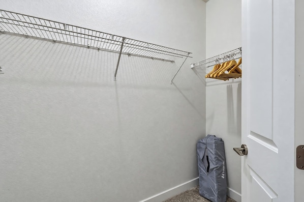 A walk-in closet with a metal drying rack and wooden hangers.