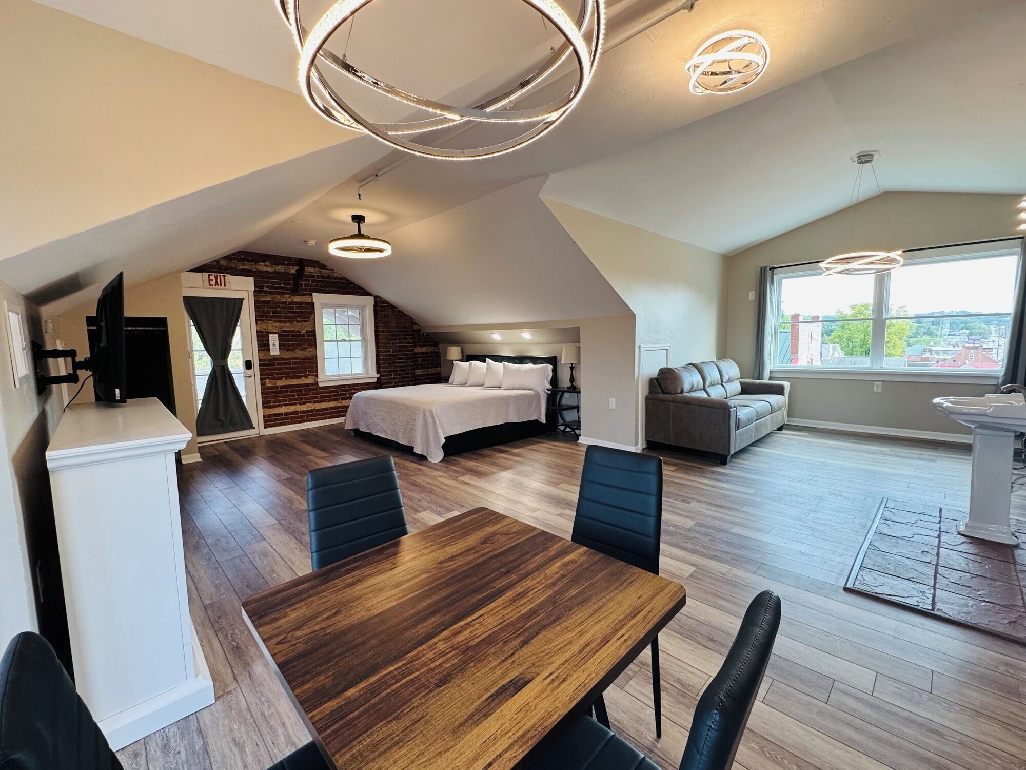 Ein modernes Schlafzimmer im Loft-Stil mit schrägem Dach, einem großen Bett, einem integrierten Schreibtisch und einer Sitzecke mit einer Couch.